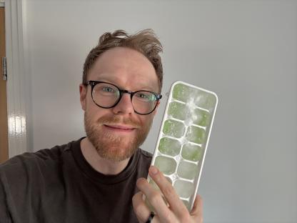 Person holding a tray of frozen ice cubes.
