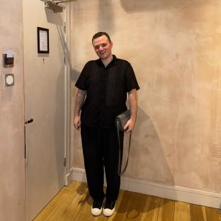 Man in black shirt and pants standing in a room.
