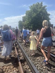 Passengers walking along train tracks.
