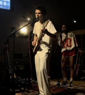 Cruz Beckham playing guitar on stage.