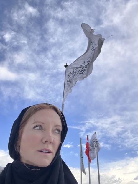 Woman in a headscarf looking up at flags.