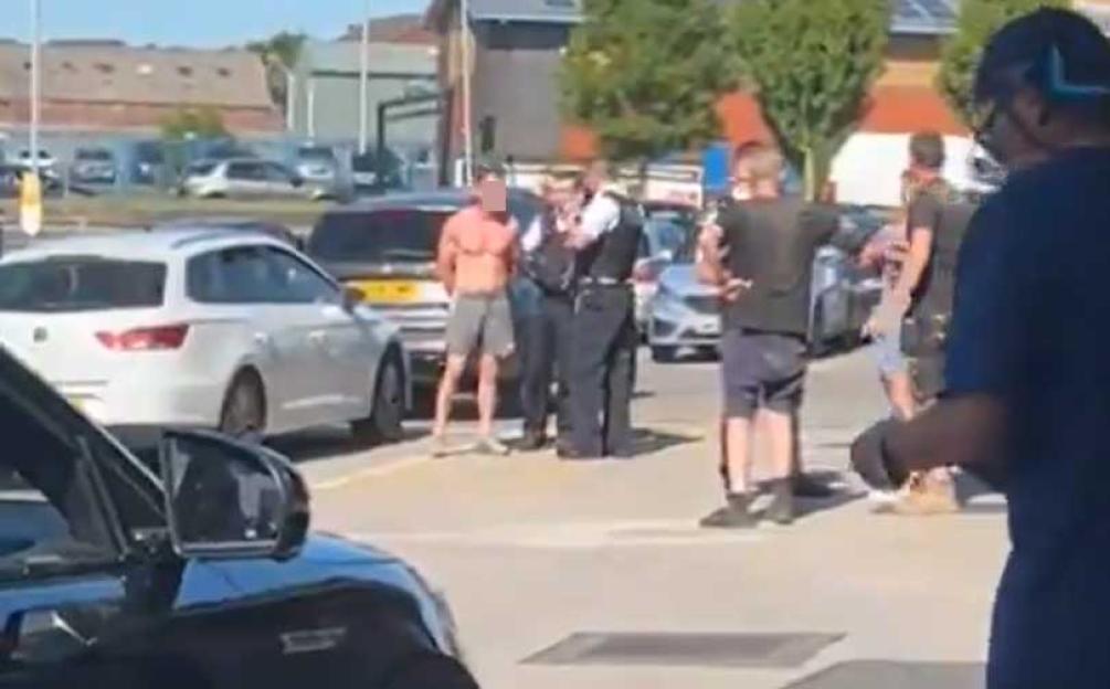 A shirtless man being arrested by police officers outside a McDonald's.