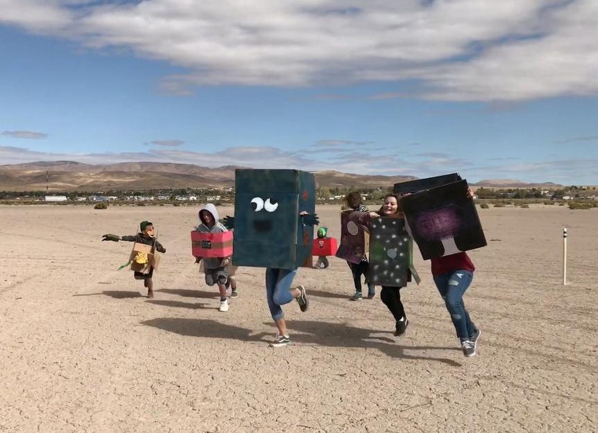 People in cardboard costumes running in a desert.
