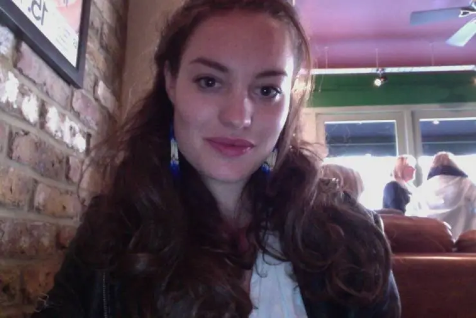 Close-up of a woman with long brown hair and blue earrings.