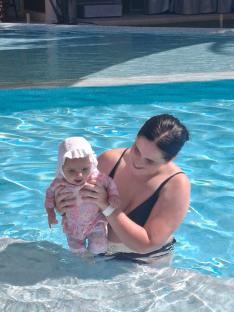 Woman holding baby in a swimming pool.