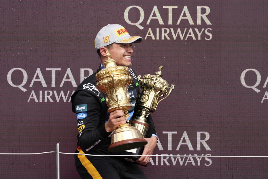 Lando Norris holding two trophies.