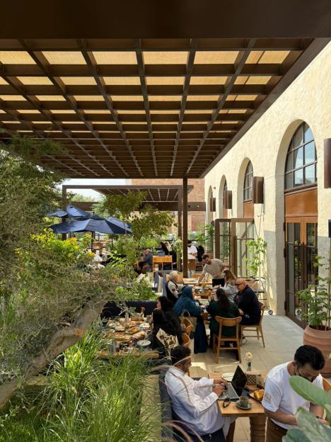 Patrons dining outdoors at a restaurant with a pergola.