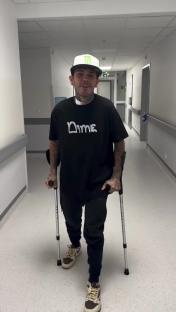 Man on crutches walking down a hospital hallway.