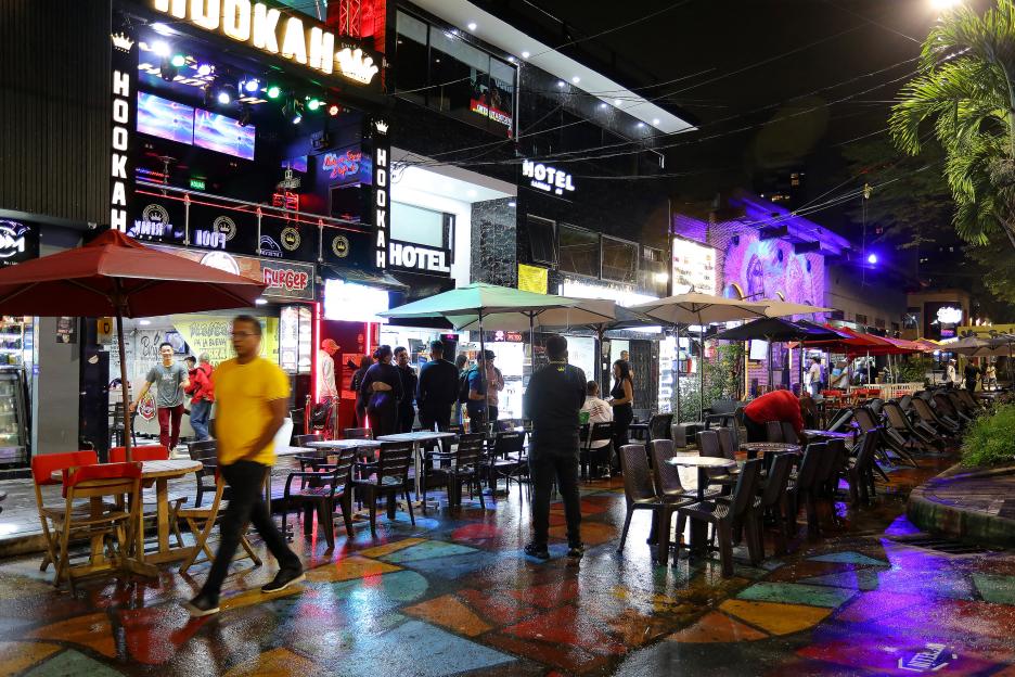 Night scene in Medellin, Colombia, showing tourists at outdoor cafes and hookah bars.