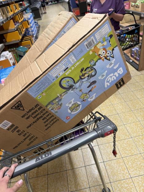 Shopping cart with a boxed Bluey children's bike.