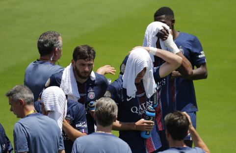 Paris Saint-Germain soccer players cooling down during a break in play.