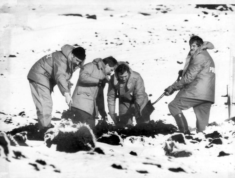 Police officers searching for bodies in the snow.