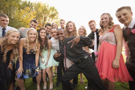 Large group of smiling teenagers in prom attire.