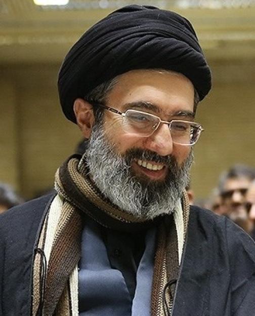 Portrait of a smiling man wearing glasses and a black turban.