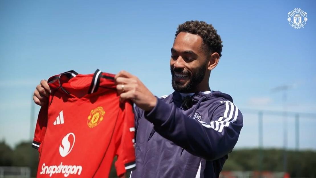 Matheus Cunha holding a Manchester United jersey.
