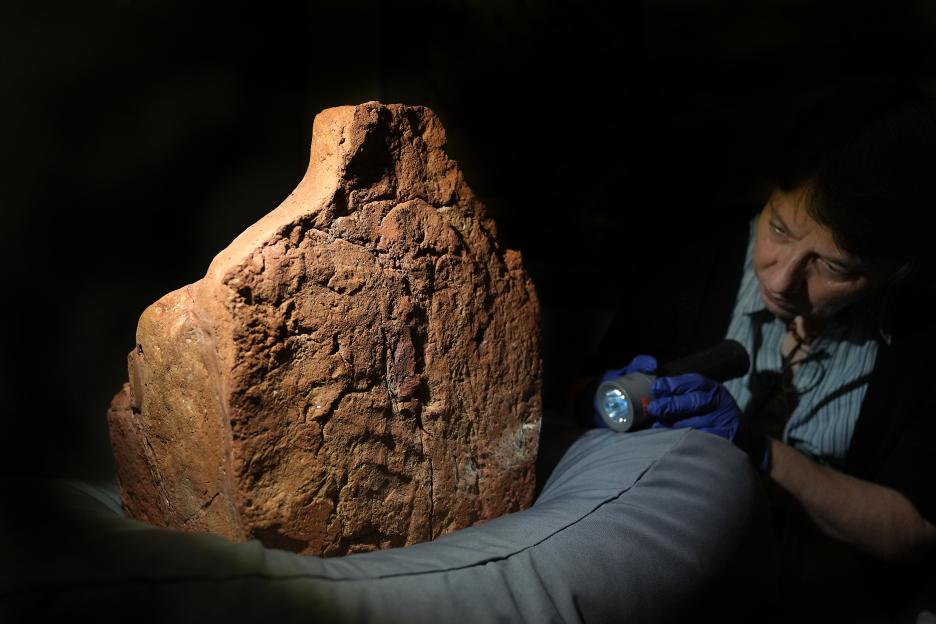 A curator examines a 4,000-year-old ancient Egyptian handprint on a soul house.