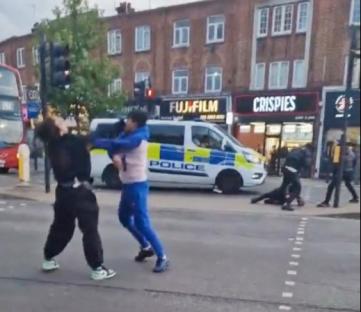 Fight breaking out in the street near a police van.