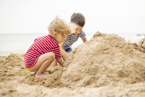 Two young boys building a sandcastle on a beach.