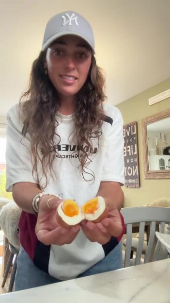 Person holding a perfectly cooked hard-boiled egg in half.