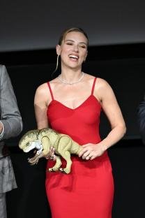 Scarlett Johansson holding a dinosaur model at a premiere.