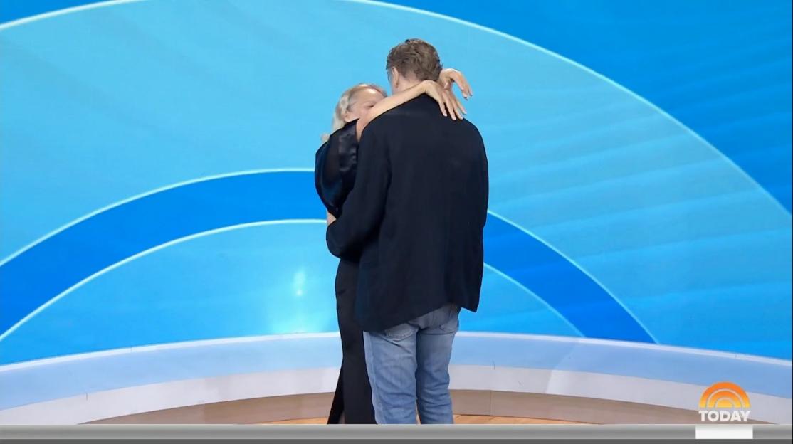 Pamela Anderson and Liam Neeson embracing on a TV show.