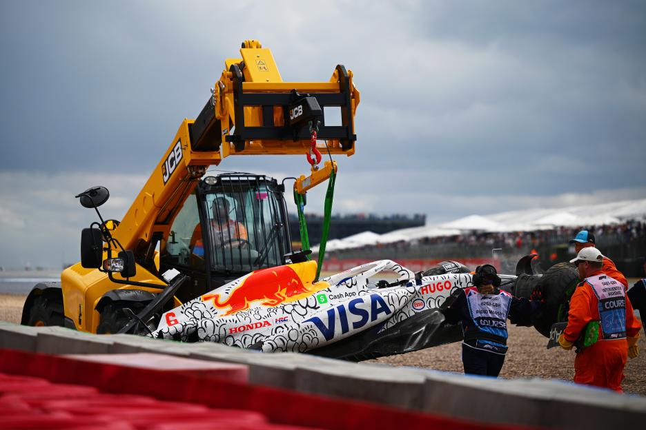 A damaged Formula 1 race car being lifted by a forklift.