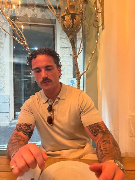 Man with tattoos sitting at a table in a restaurant.