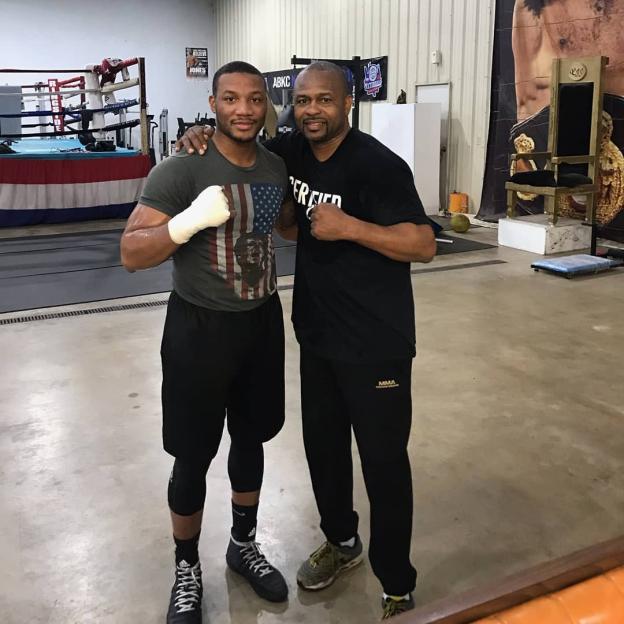 Two boxers posing together in a gym.