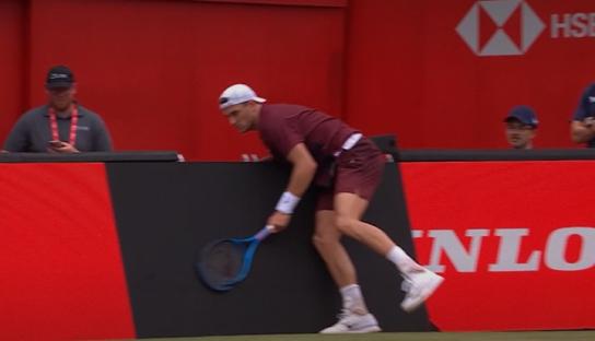 Tennis player reaching for a tennis ball.