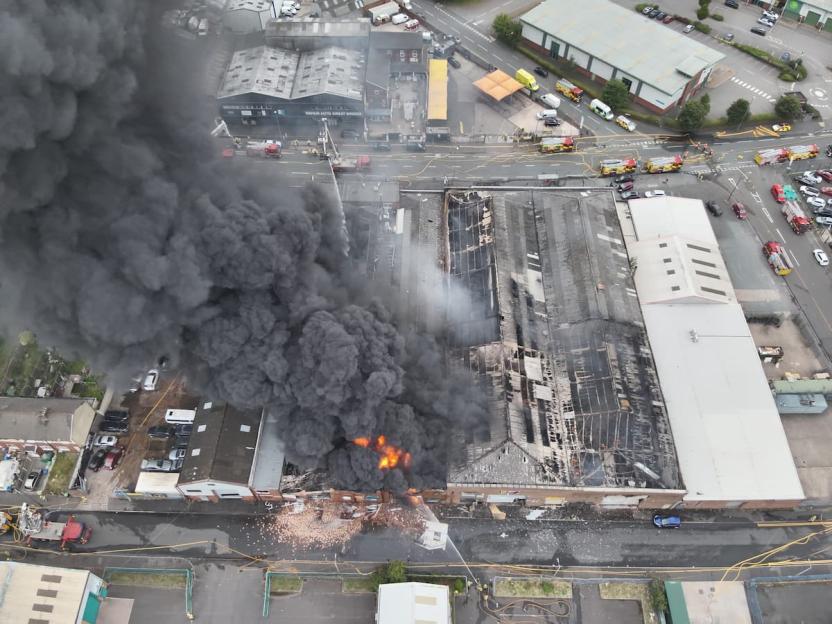 Aerial view of a large building fire with significant smoke.