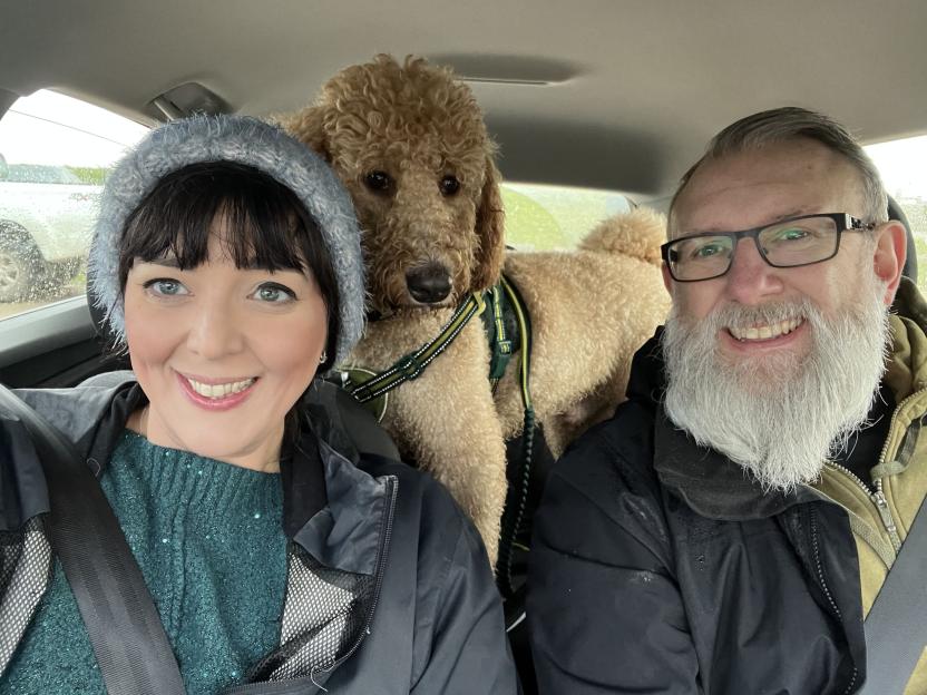 A couple and their large Bernedoodle dog in a car.