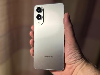 A hand holding a silver Samsung phone.