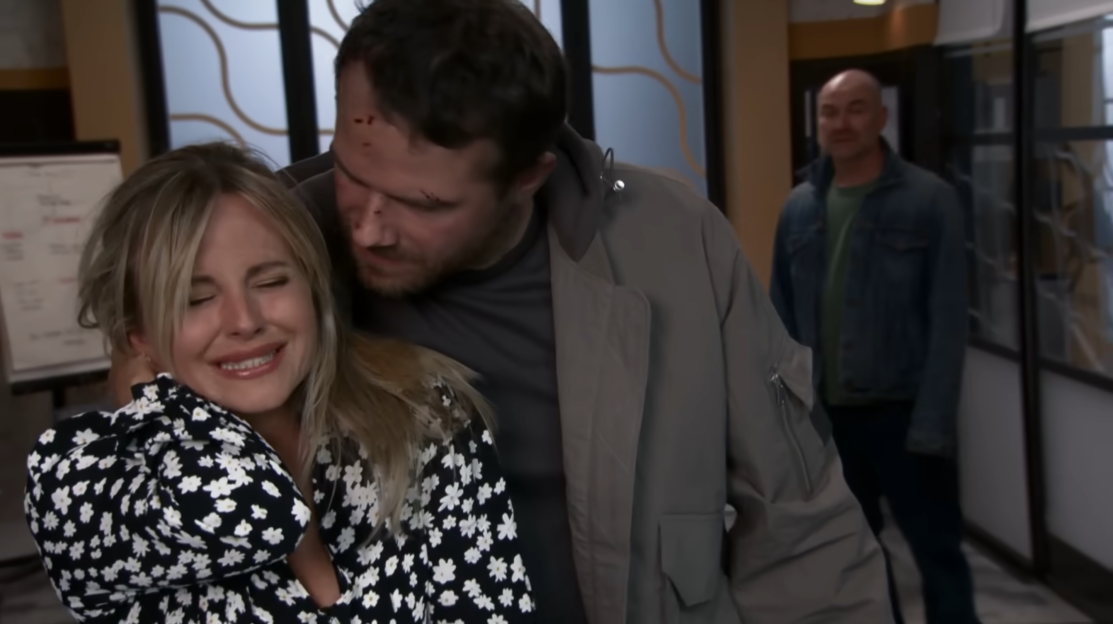 Screenshot of a woman crying while a man comforts her; another man stands in the background.