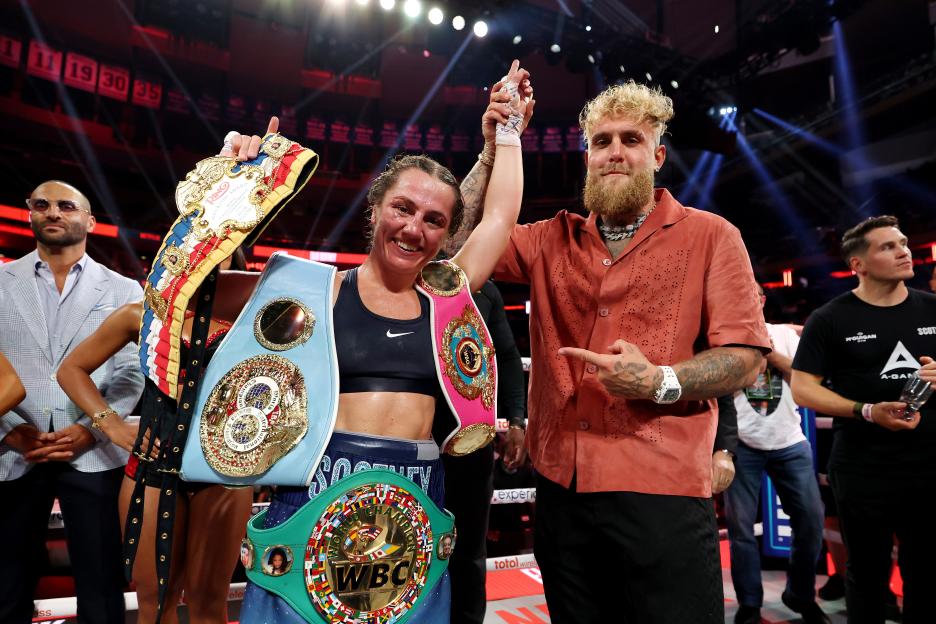 Ellie Scotney and Jake Paul celebrating a boxing victory with championship belts.
