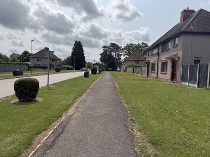 Residential street scene with homes and a pedestrian path.