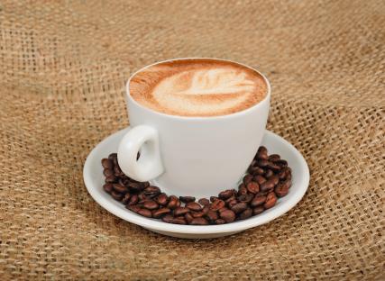 Cappuccino in a white cup with coffee beans.