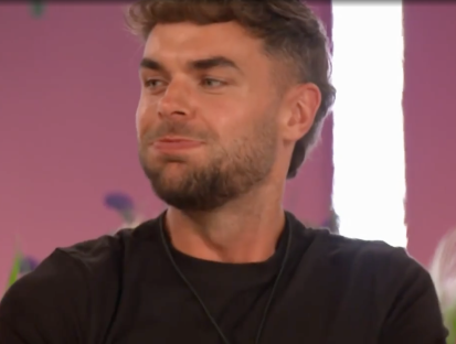 Screenshot of a man with short brown hair and a beard, wearing a black shirt.