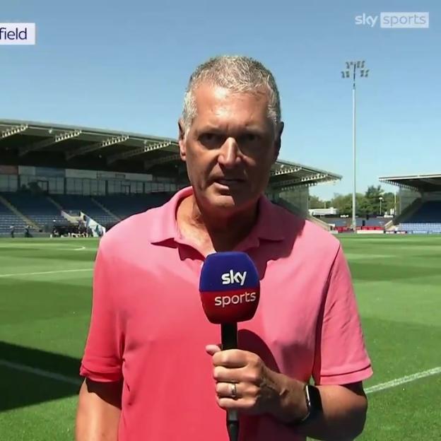 Sky Sports reporter Alan Irwin reporting live from a soccer field.