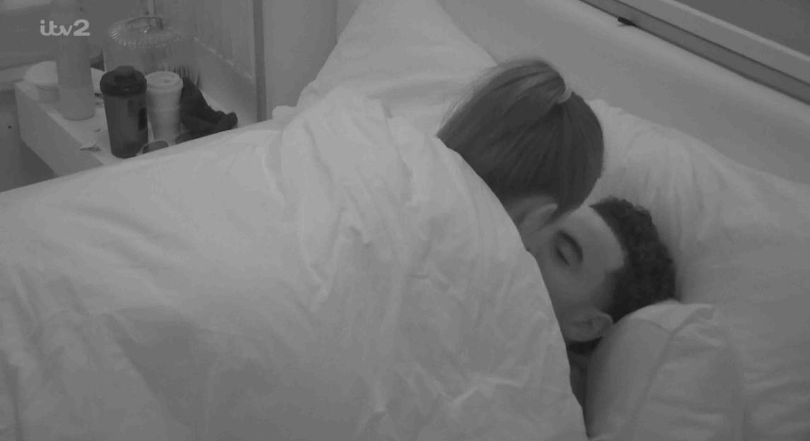 Couple under covers in bed.