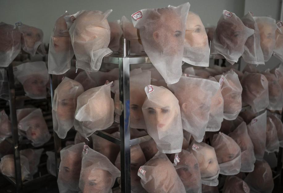 Heads of silicone sex dolls in protective bags at a factory.