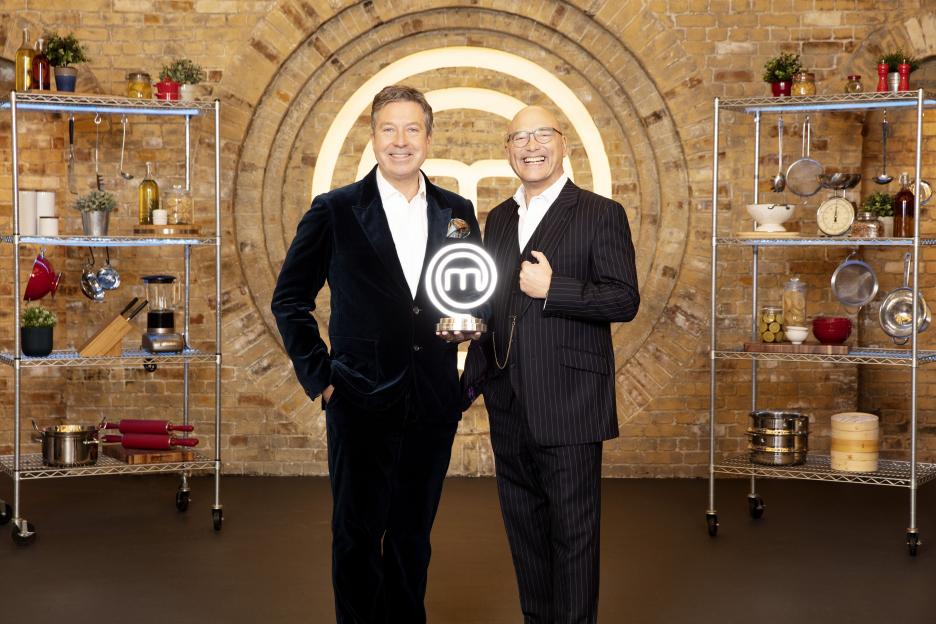 John Torode and Gregg Wallace holding a MasterChef trophy.