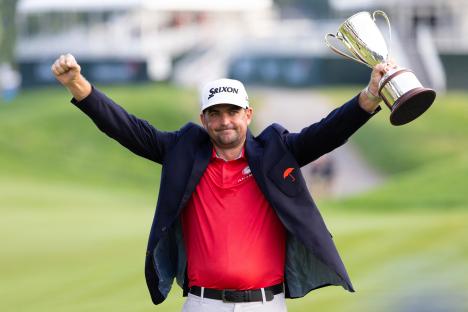 Keegan Bradley holding up the Travelers Championship trophy.