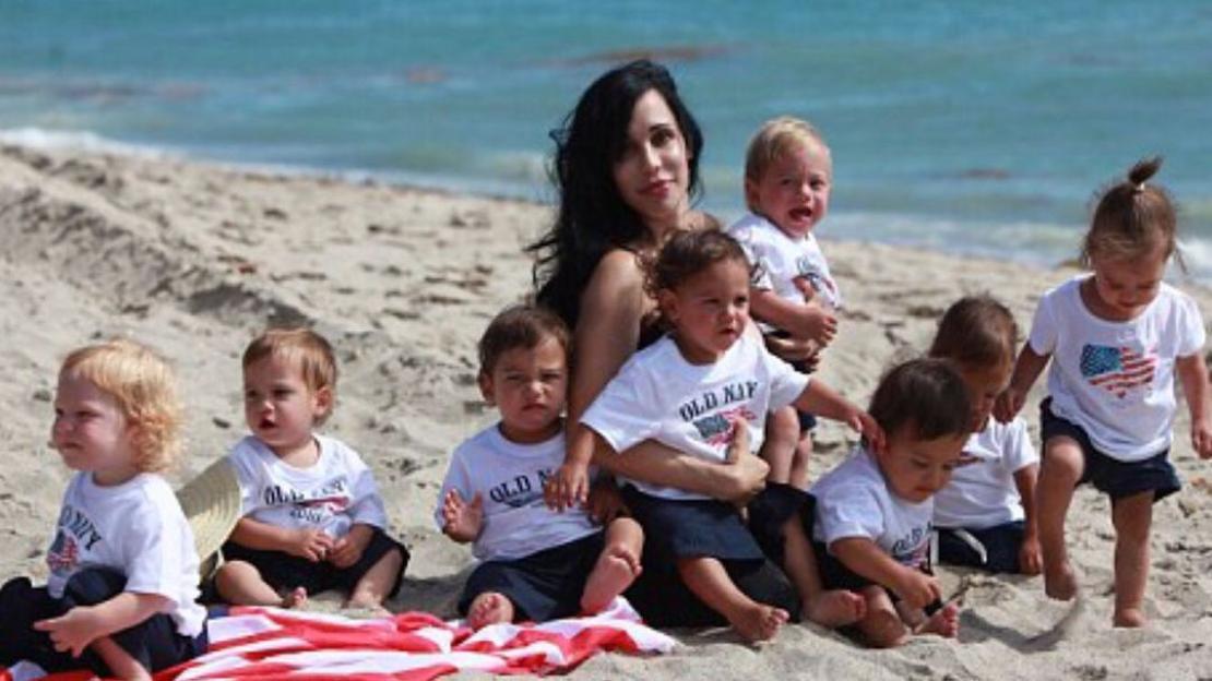 A woman on a beach with her eight children.