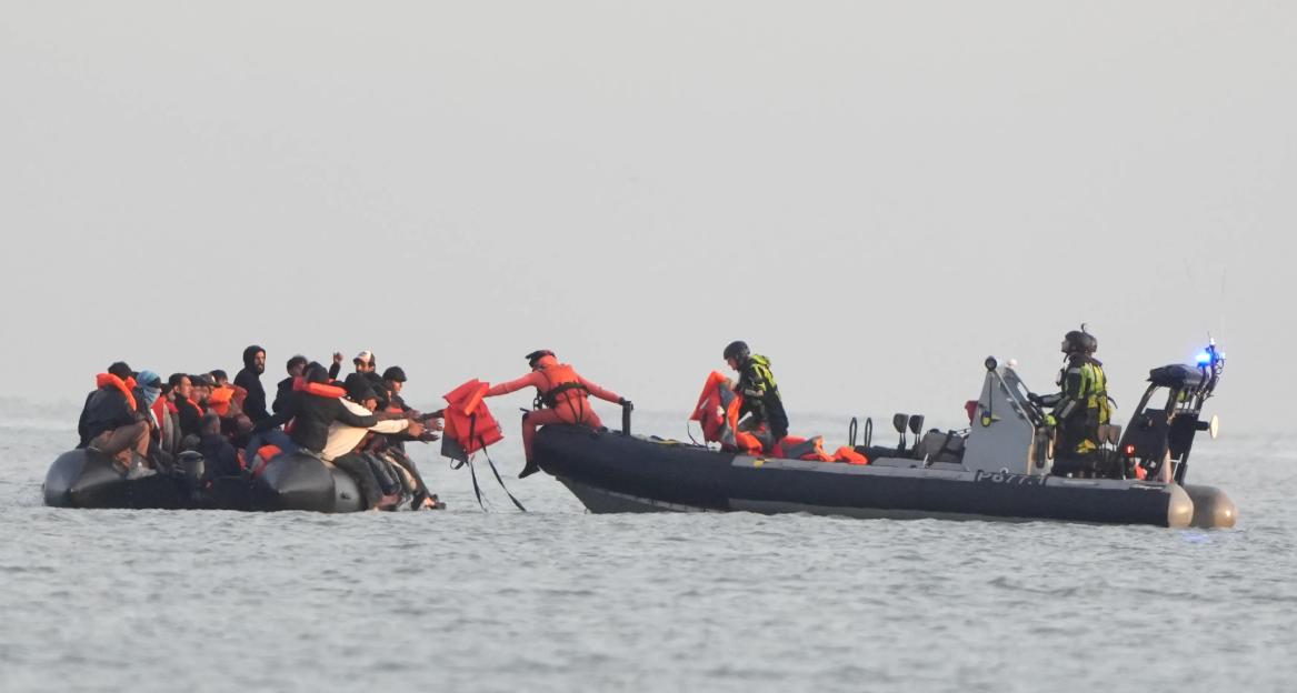 Migrants in an inflatable boat being given life jackets by French authorities.