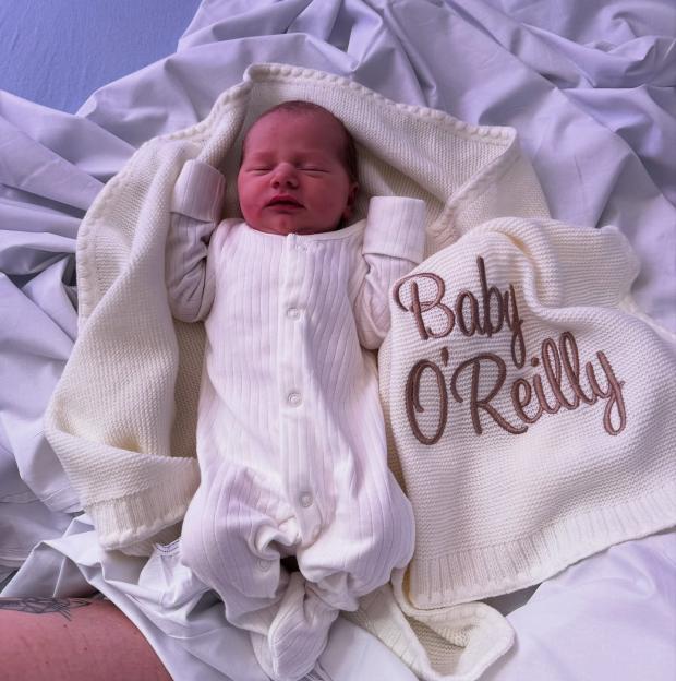 Newborn baby girl swaddled in a white blanket.