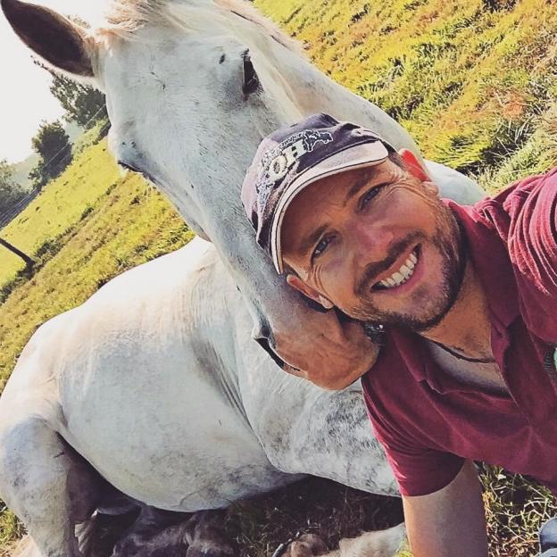 Man hugging a white horse.