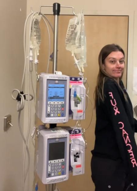 Woman standing near an IV drip stand during chemotherapy treatment.