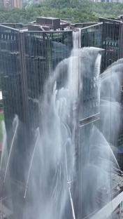 Tethered drones spraying water onto a high-rise building during a fire drill.