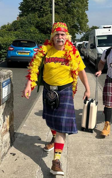 Man in Hulk Hogan costume and kilt walks with friends.