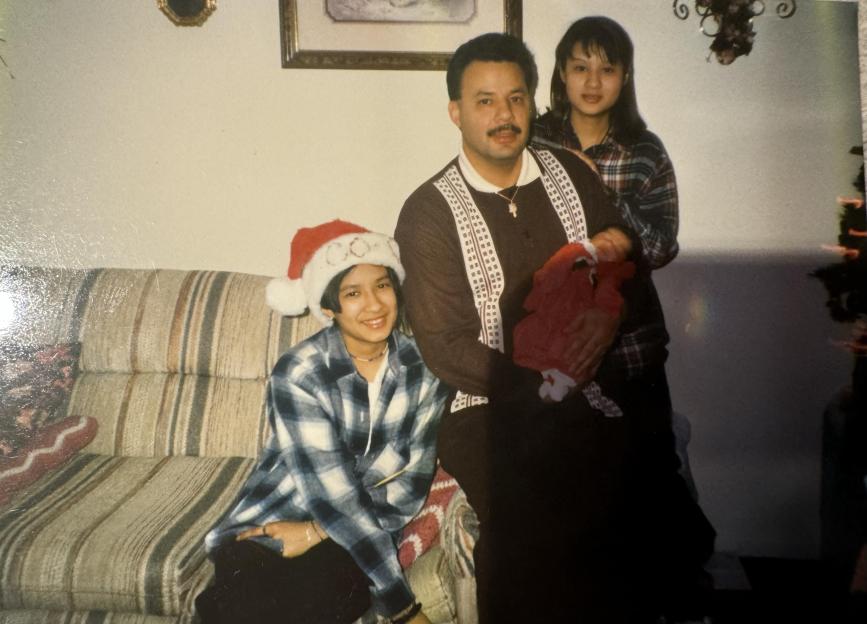Family photo of a man, two girls, and an infant.
